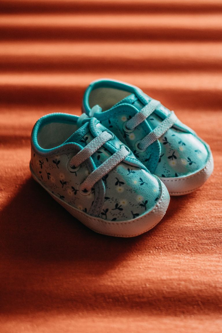 Close-up of cute blue baby shoes with floral pattern on warm, textured background.